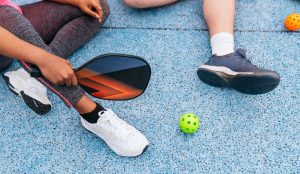 at the pickleball court with paddles and ball