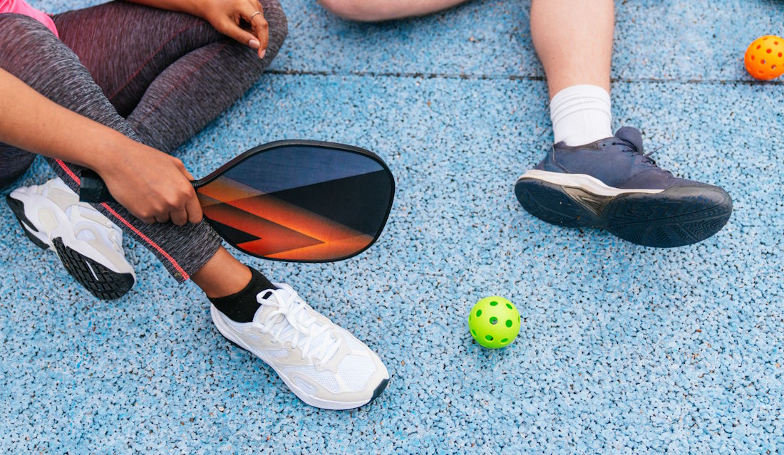 at the pickleball court with paddles and ball